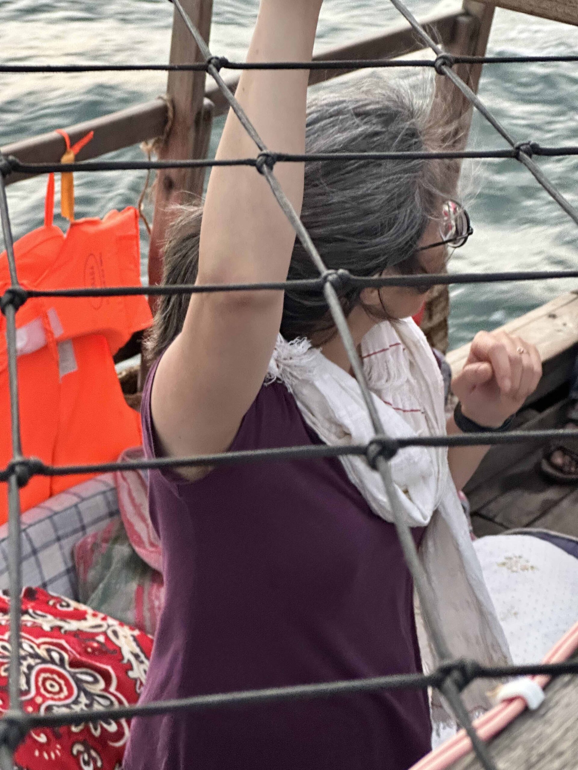 Woman in a purple shirt on a boat with her arm raised